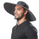 Un homme portant un chapeau de brousse noir à large bord sur un fond blanc