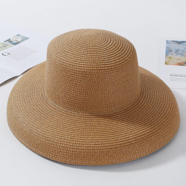 chapeau en paille marron à bords larges pour femme sur fond blanc avec des livres et des photos