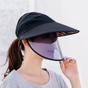 Femme portant un grand chapeau noir et une visière anti-UV violette.