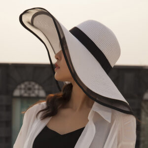 Femme portant une capeline blanche et noir de profil avec un chemise blanche et un haut noir