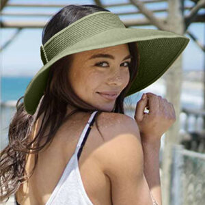 Femme en débardeur blanc portant un chapeau en paille vert sous un parasol de bar de plage.