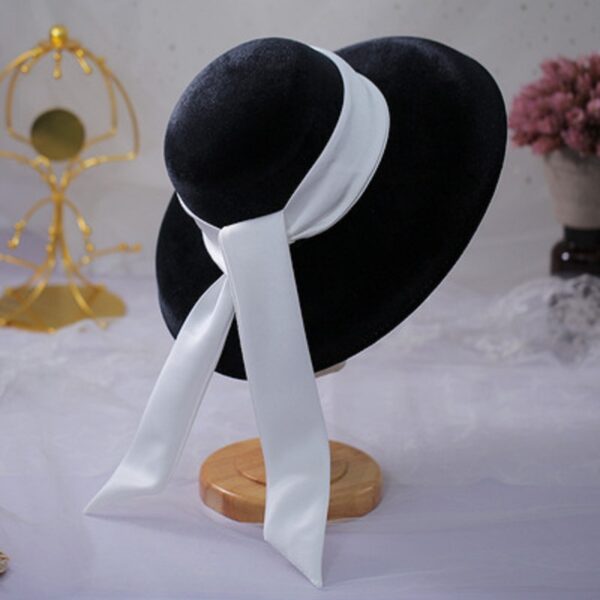 Photo d'un chapeau breton noir avec un ruban blanc sur un porte chapeau sur une nappe blanche