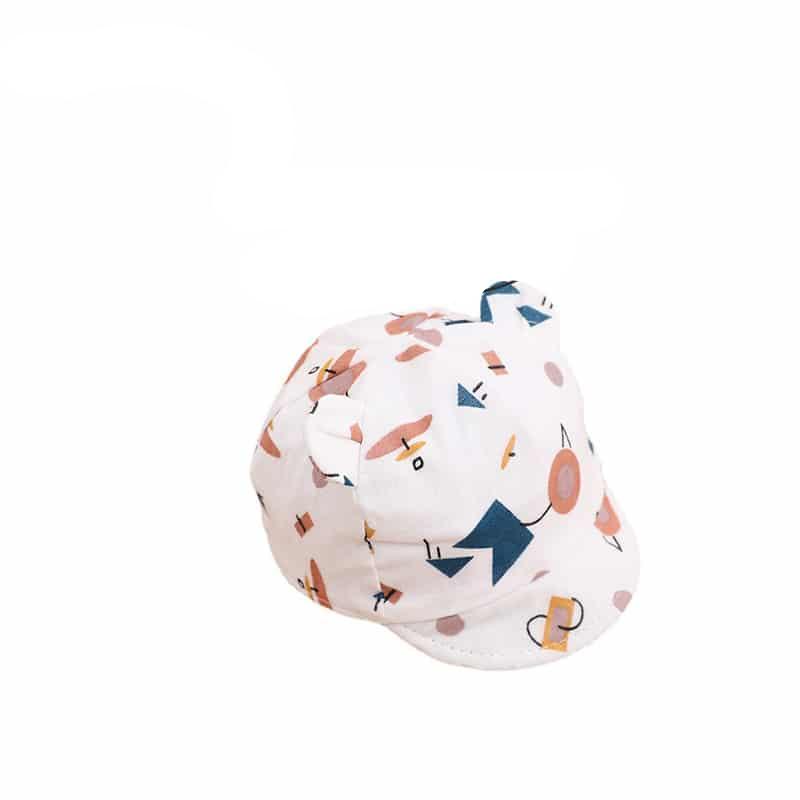 Jolie casquette en coton blanche avec des motifs de toutes les couleurs joyeux. Le chapeau est surmonté d'oreilles d'ourson.