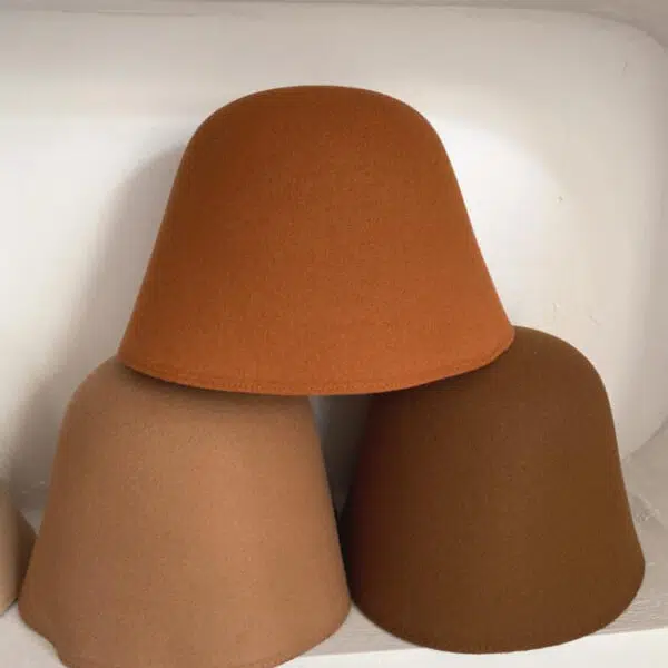 Trois chapeaux cloches exposé les uns sur les autres. Ils sont caramel, marron et kaki.
