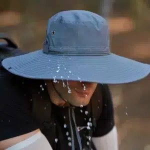 Homme portant un chapeau gris de randonnée avec des gouttes d'eau qui tombent sur le chapeau
