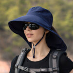 Chapeau anti UV bleu marine pour femmes, avec cordon de serrage porté par une mannequin avec lunette de soleil