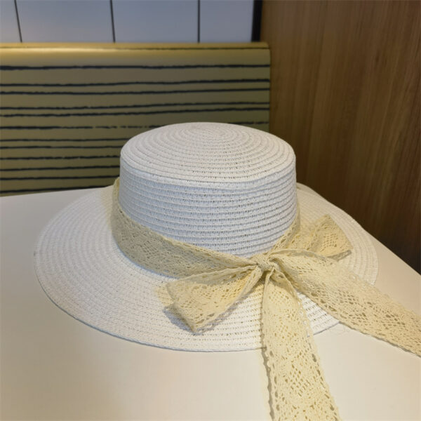 Chapeau plat blanc, en paille, entouré par un ruban en dentelle blanc avec nœud papillon