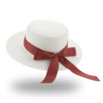 Chapeau plat blanc, en paille, entouré par un ruban rouge avec noeud papillon