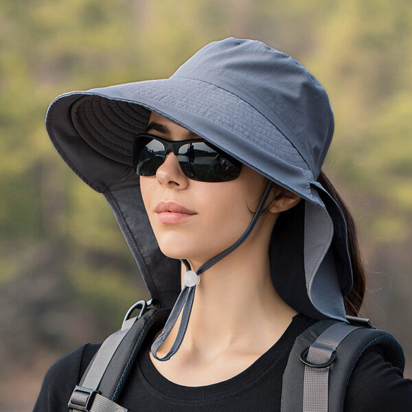 Chapeau anti UV gris foncé pour femmes, avec cordon de serrage porté par une mannequin avec lunette de soleil