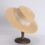 Un chapeau de paille avec ruban posé sur un socle en bois