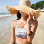 Chapeau en paille, tissé à la main, à bords large, pour femmes, porté par une mannequin en maillot de bain à la plage