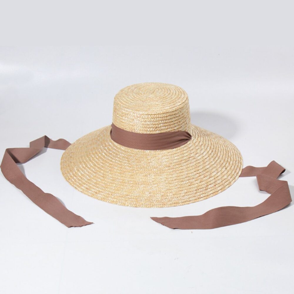 un chapeau de paille avec ruban marron sur fond blanc.