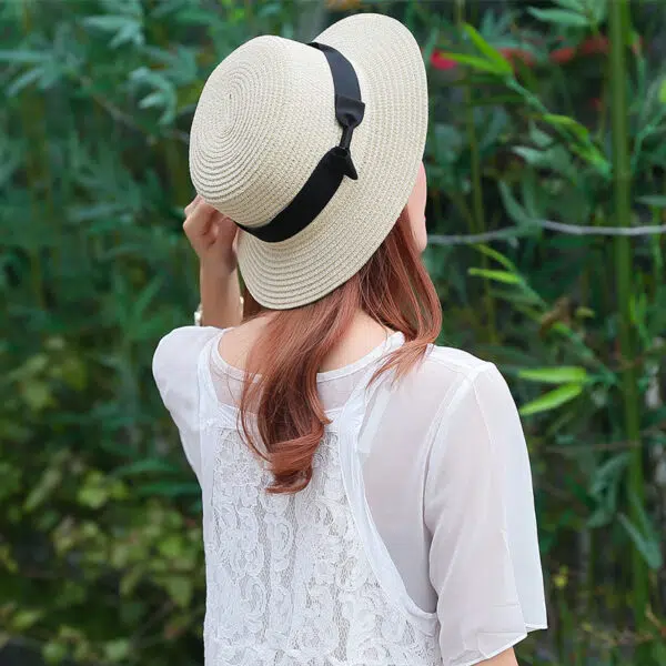 Chapeau panama blanc de plage avec nœud papillon noir pour femmes porté par une femme de dos