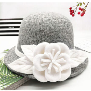 Chapeau cloche vintage en laine florale pour femme de couleur gris avec un motif floral blanc, posé sur une table blanche