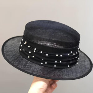 Chapeau canotier de mariage noir transparent avec ruban noir et perles tout le tour. Tenu par une main.