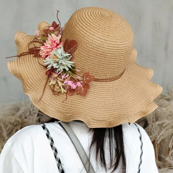Femme de dos portant un chapeau de paille couleur naturelle, avec des fleurs sur le coté