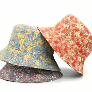 3 chapeaux bob fleuris style liberty, sur fond blanc. Il yen a un mauve, un bleu et un rouge orangé.
