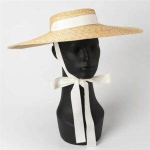 Chapeau canotier en paille avec large ruban blanc, noué sur une tête à chapeau